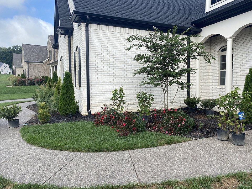 White brick house with black trim and a landscaped yard with a curved sidewalk.