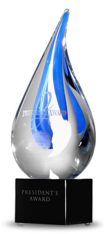 A glass tear-drop shaped award with a blue swirl center, mounted on a black square base labeled 