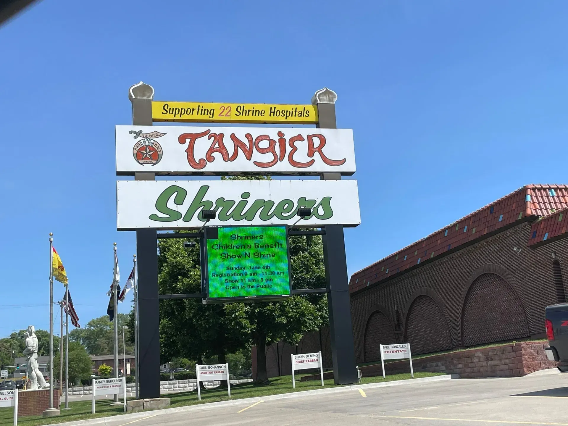 A sign for Tangier Shriners stands under a clear blue sky, with a digital message board below on a sunny day.