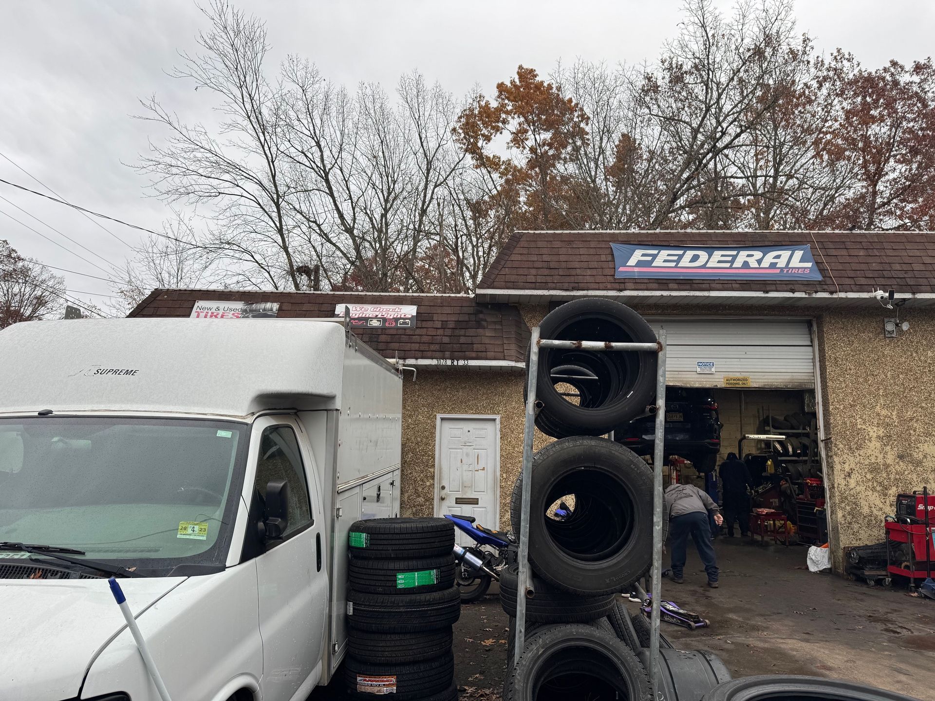 A Federal tire shop exterior with a white van, tires, and a person entering. Overcast day.
