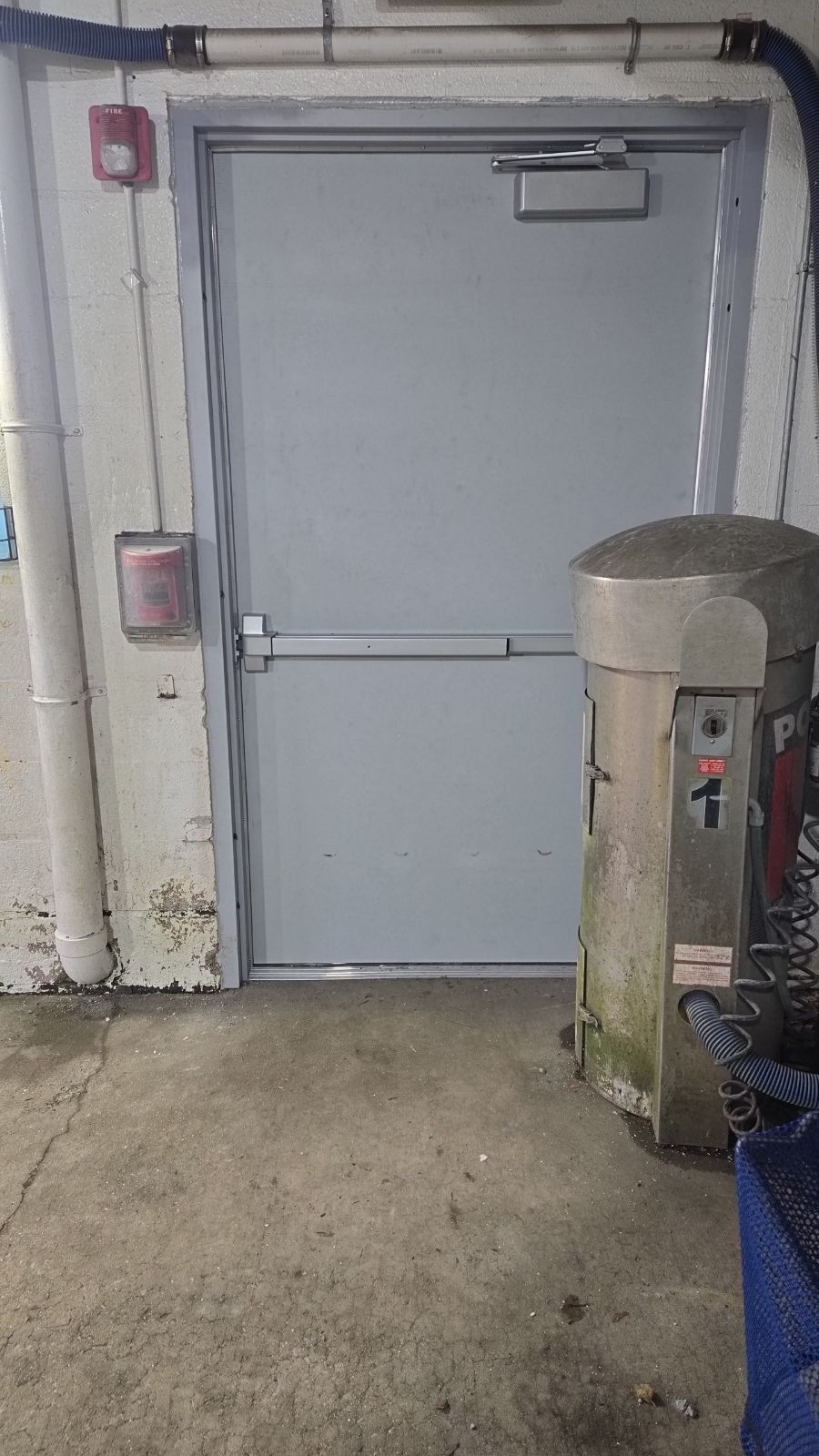 A room with a door and a trash can in it.