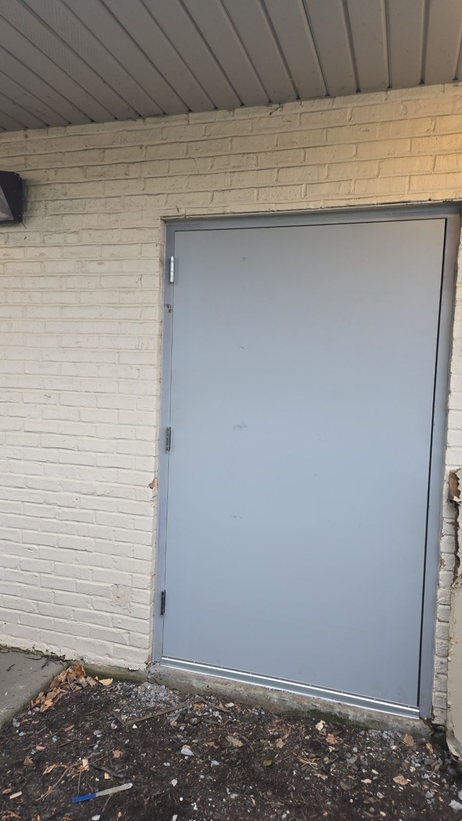 A white brick building with a large door on the side.