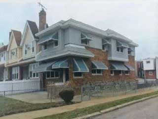A brick house with awnings on the windows and a chimney on top of it.