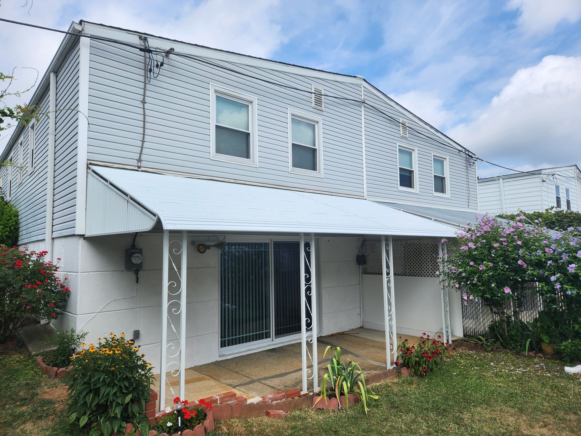 A white house with a white awning on the porch.