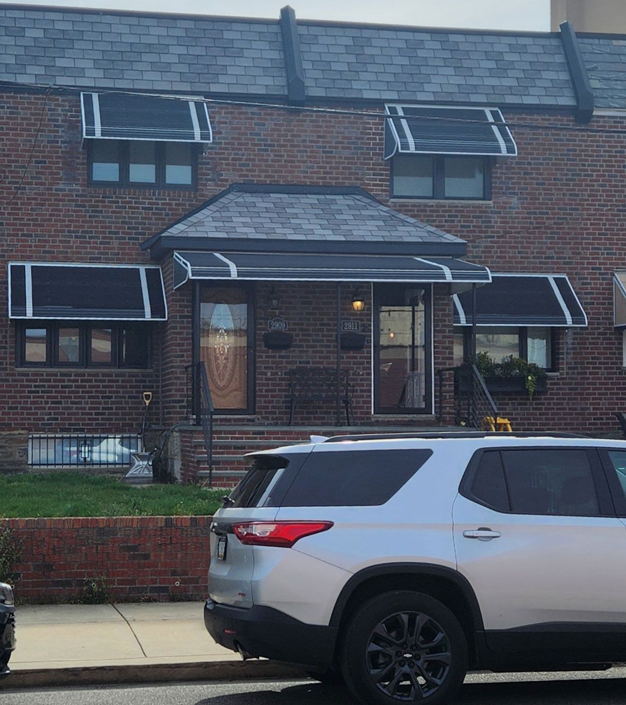 A silver SUV is parked in front of a brick house.
