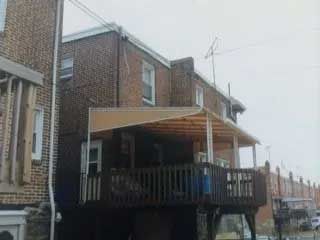 A brick house with a large deck and a canopy over it.