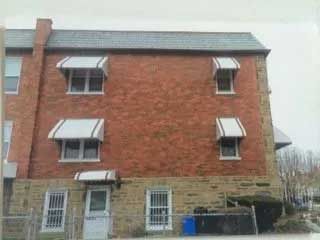 A brick building with white awnings on the windows.