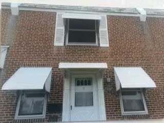 A brick building with a white door and awnings on the windows.