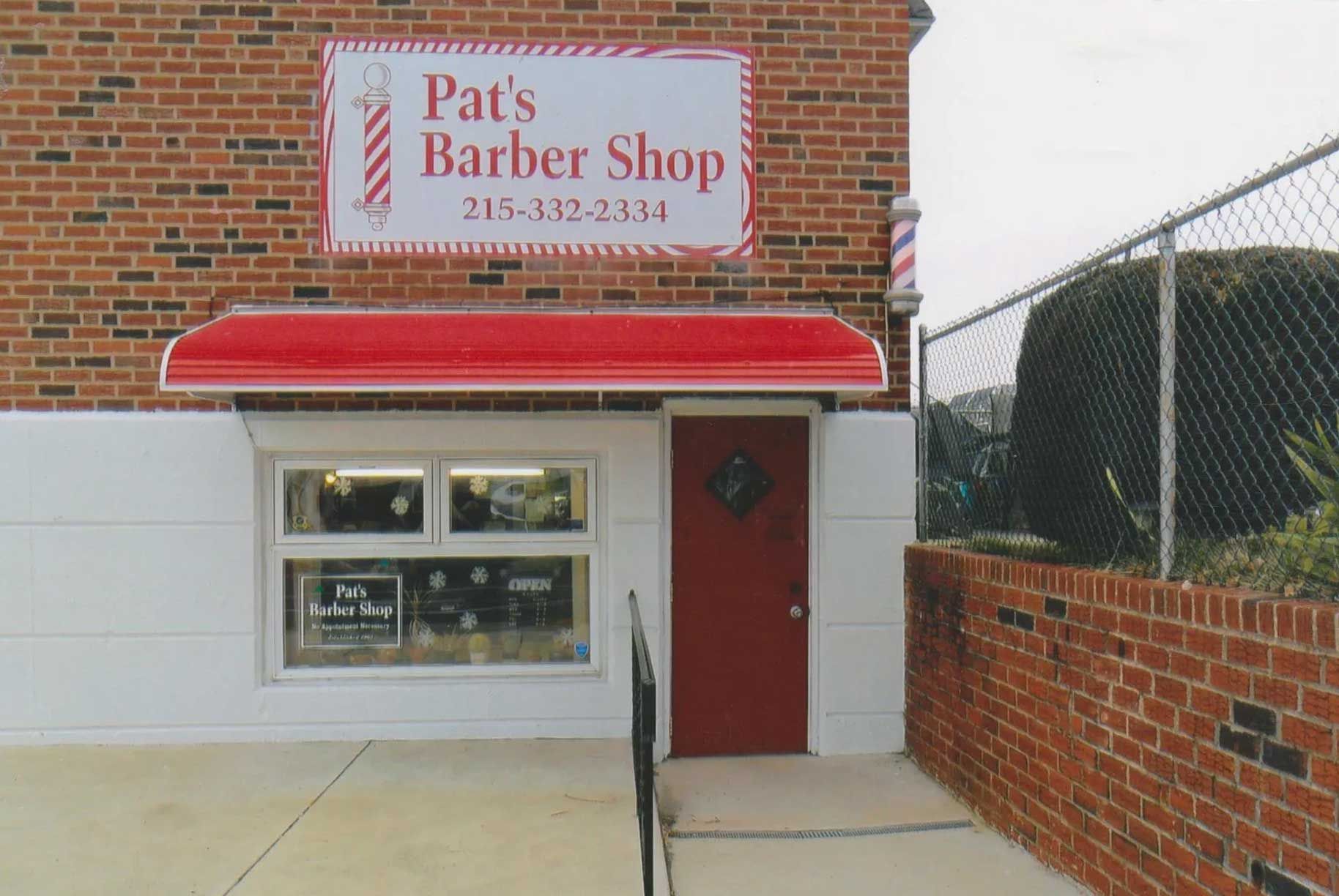 The outside of pat 's barber shop with a red awning