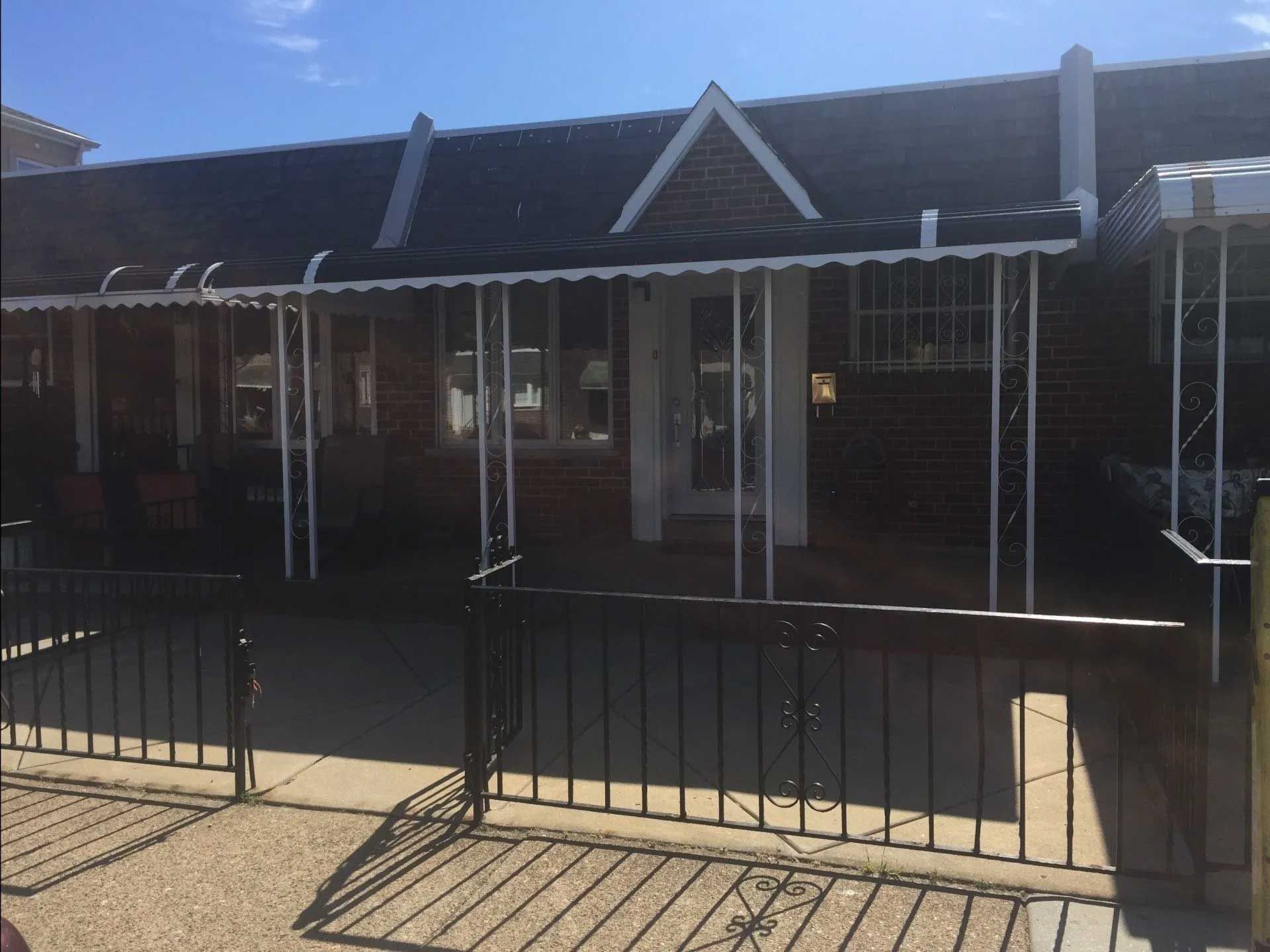 A brick building with a white awning and a fence