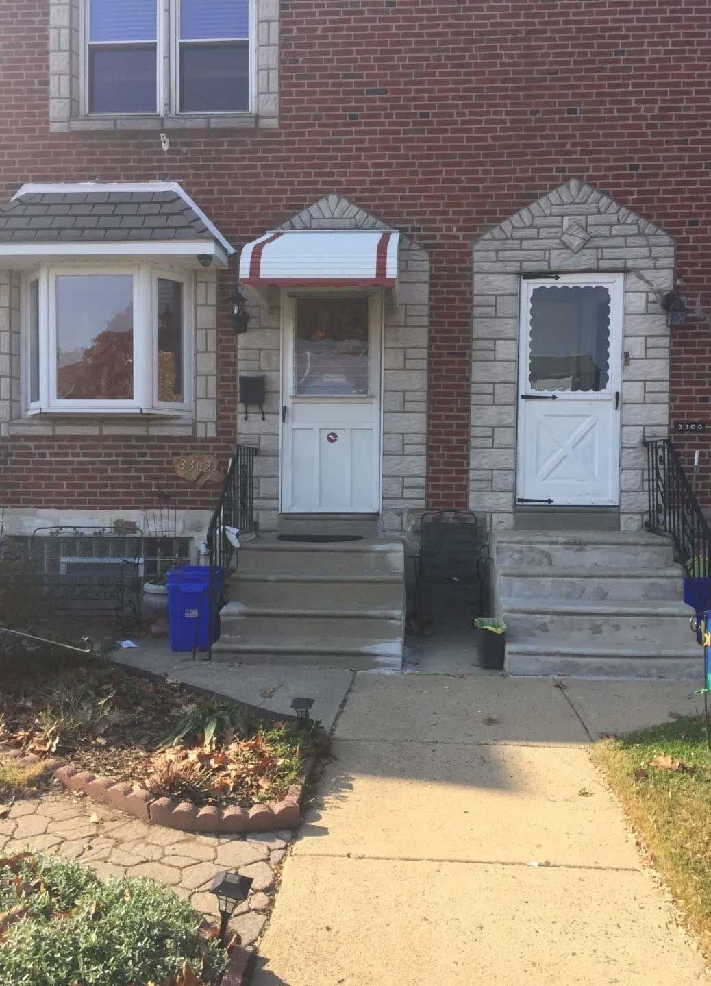 A brick building with two white doors and a red awning.