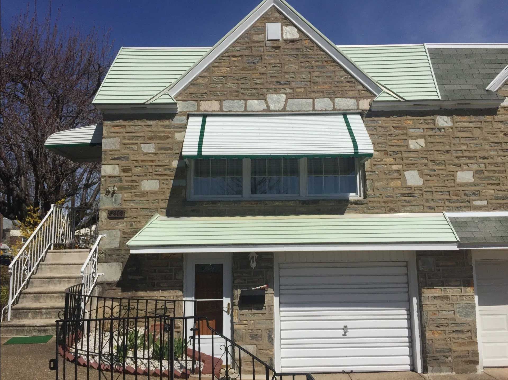 A brick house with a white garage door and a green awning