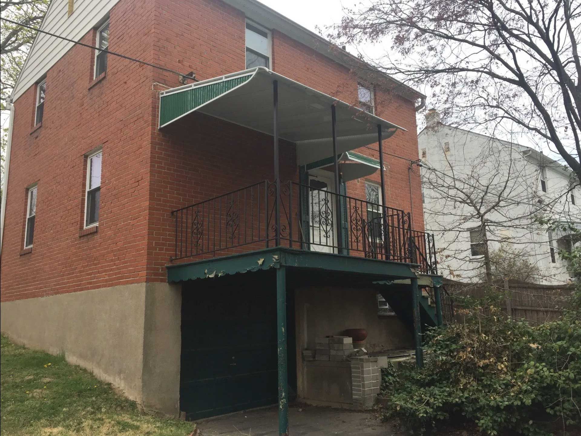 A brick house with a balcony and a green awning.