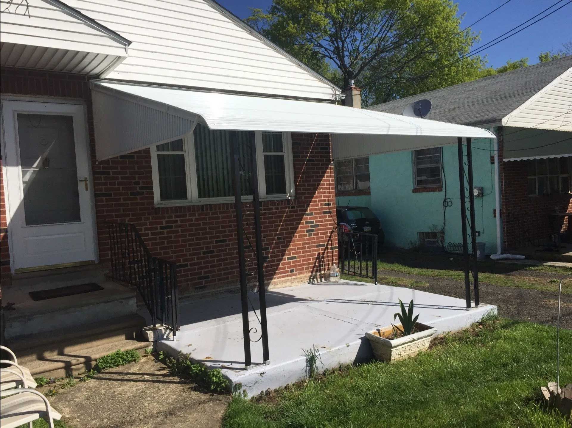 A white awning is sitting on the side of a brick house.