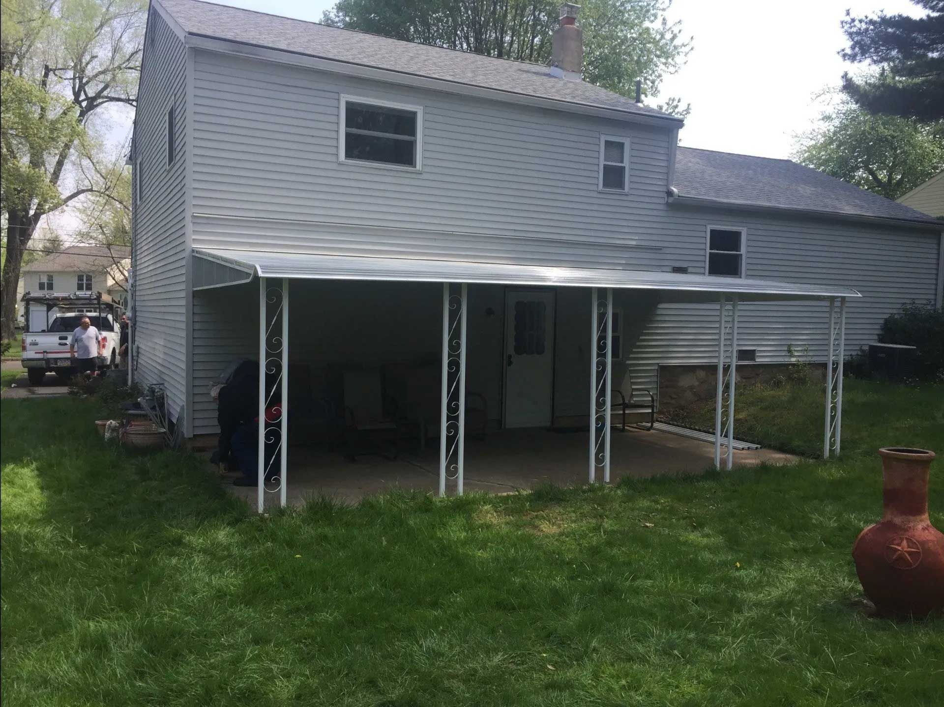 A white house with a covered porch in the backyard.