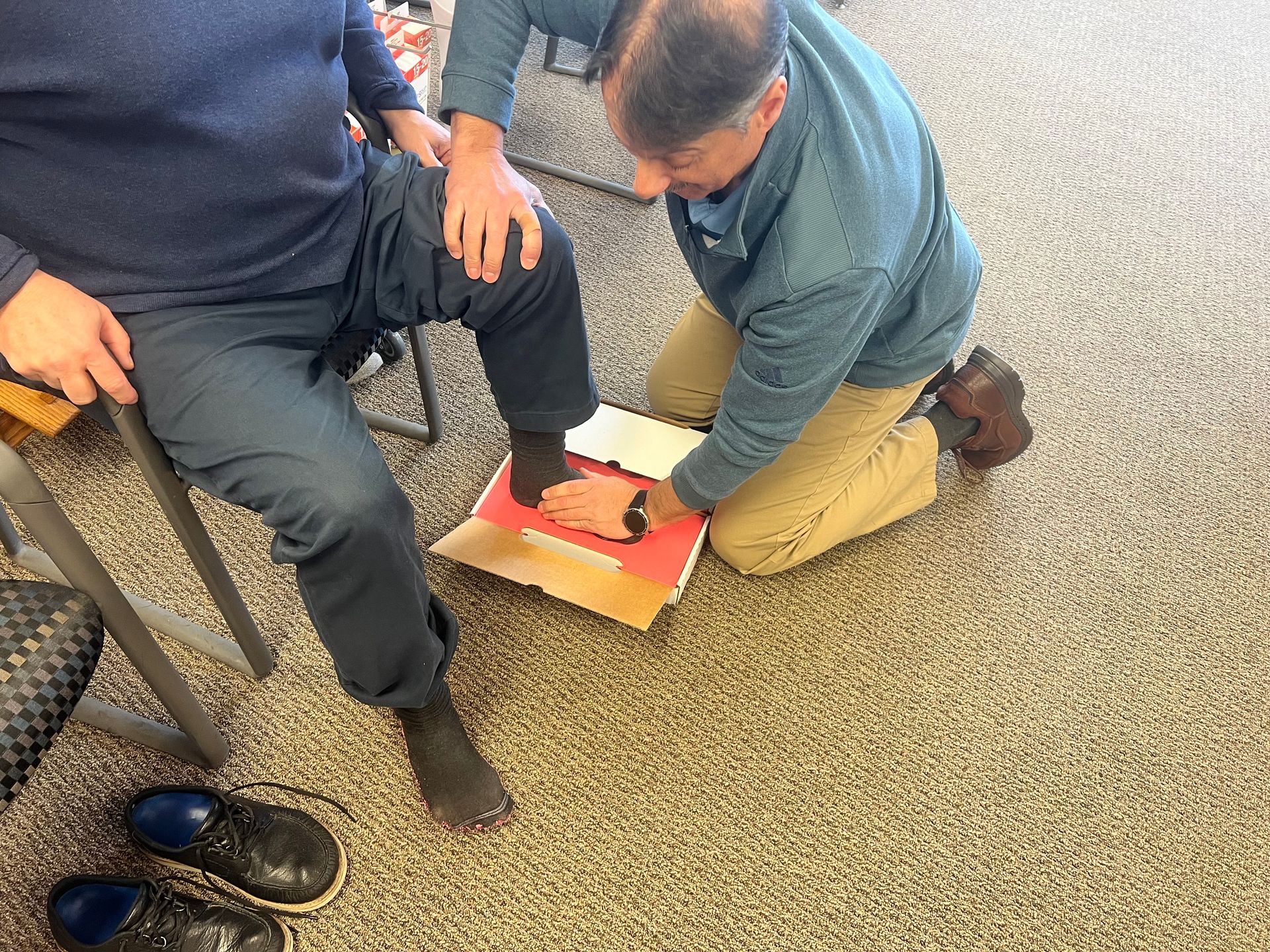 A man is kneeling down next to another man 's leg.