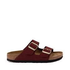 A pair of burgundy birkenstock arizona sandals on a white background.