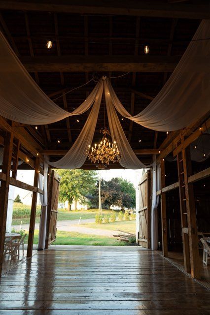 The inside of a barn with a chandelier hanging from the ceiling.