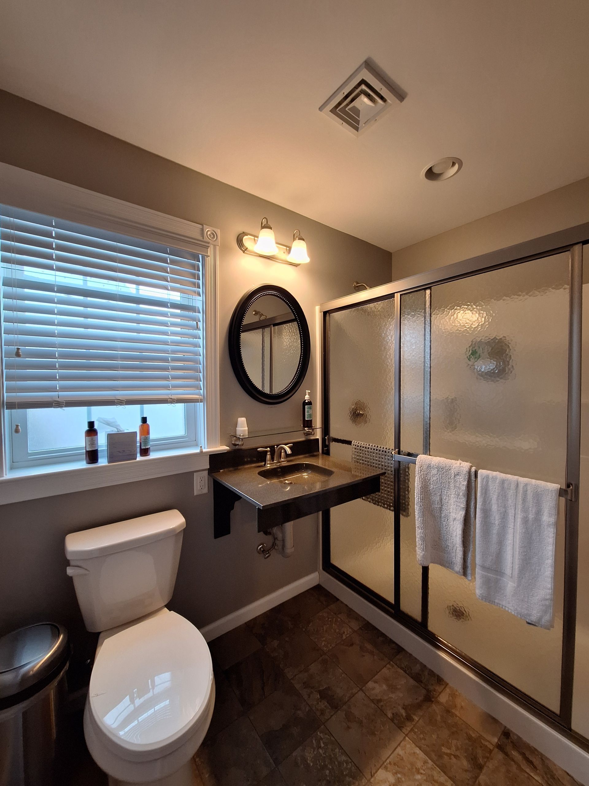 A bathroom with a toilet , sink and shower.