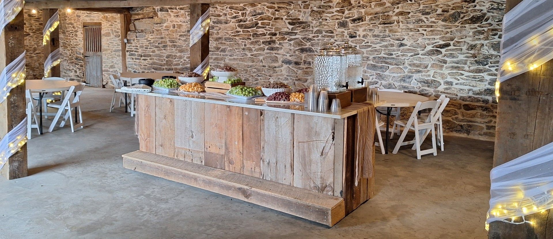 Rustic buffet table with food and drinks in a stone-walled room