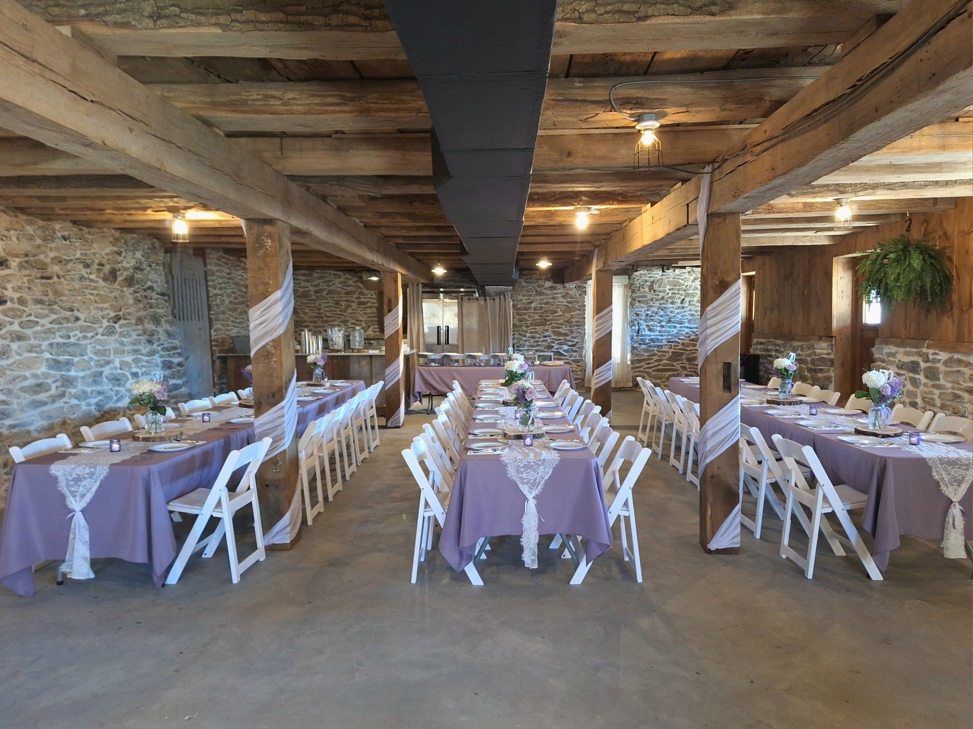 Indoor banquet hall with long lavender tablecloth tables and white folding chairs, set for an event