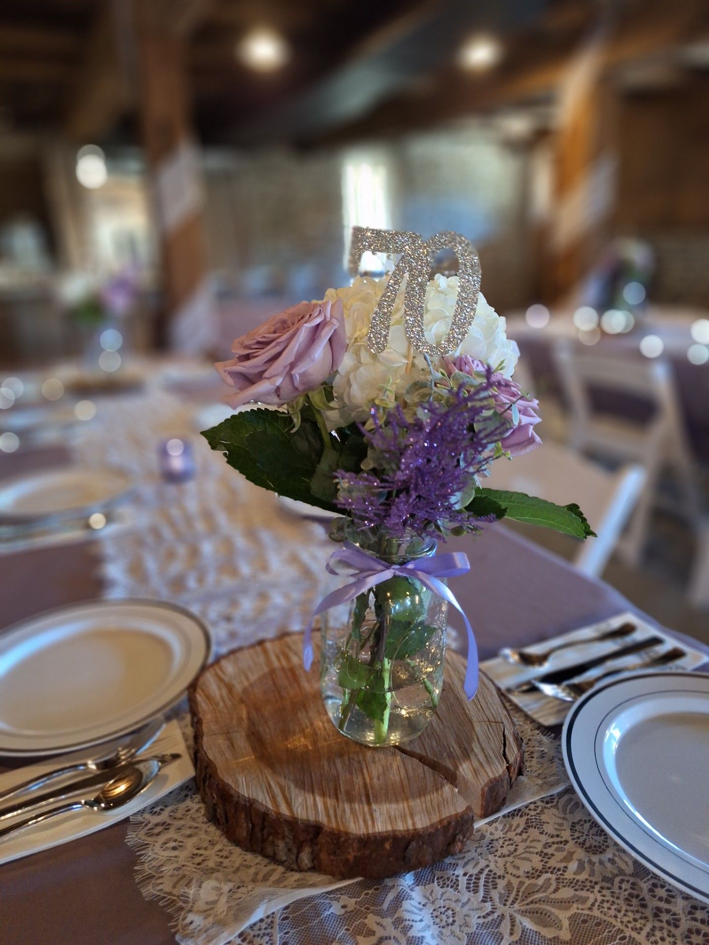 Floral centerpiece in a small glass vase on a wooden slice atop a decorated dining table