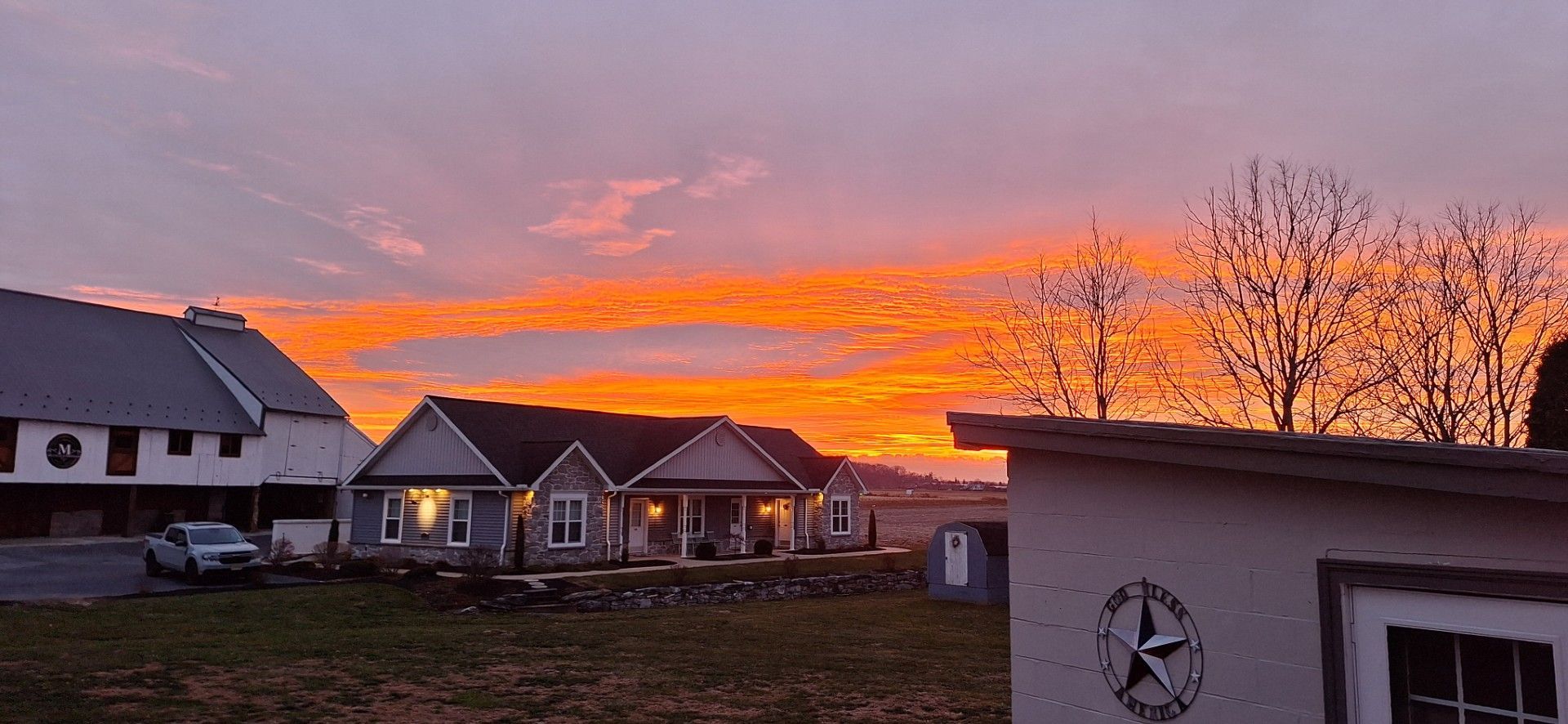 Sunset over suburban houses and bare trees, with a bright orange and pink sky