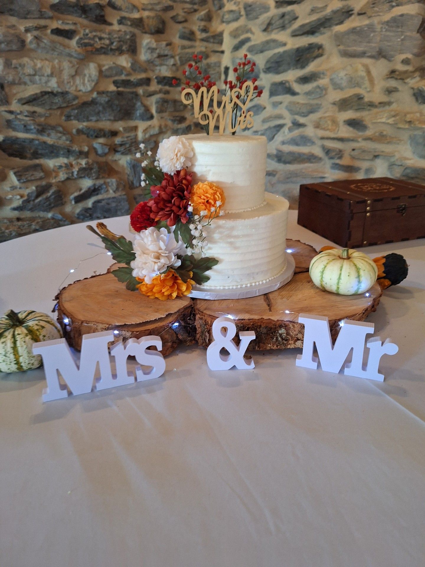 Wedding cake on a rustic table with white Mrs & Mr letters and fall floral accents