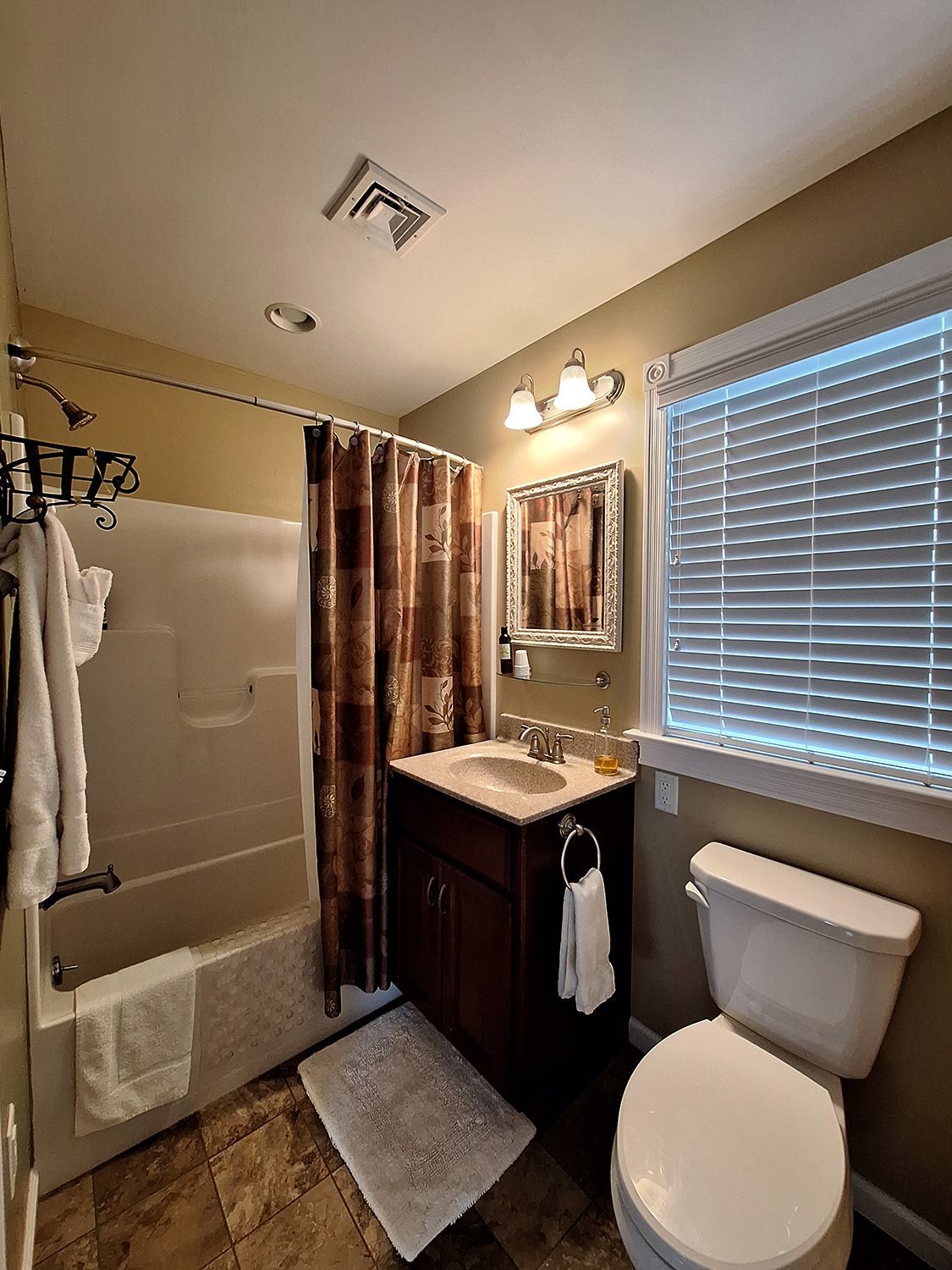 A bathroom with a toilet , sink , tub and mirror.