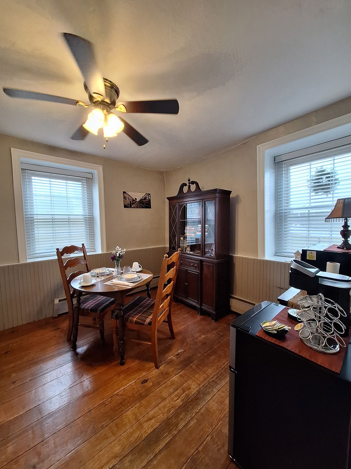 A dining room with a table and chairs and a ceiling fan.