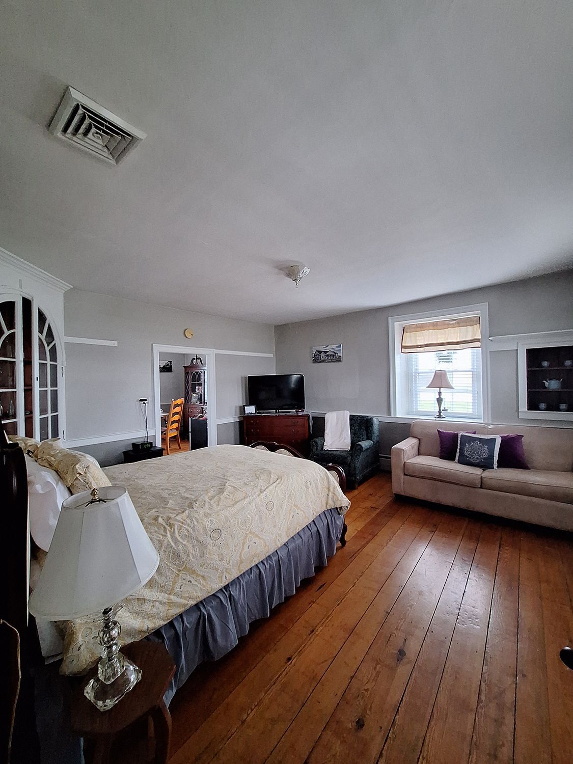 A bedroom with a large bed , couch , chair and television.
