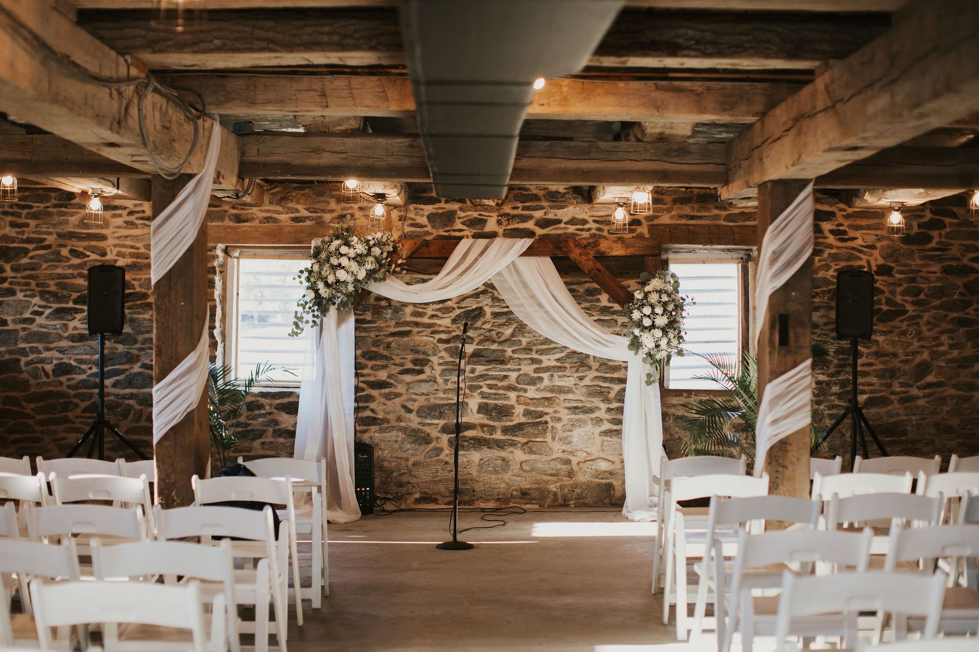 A large room with tables and chairs and a stone wall