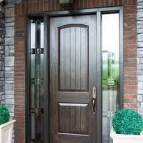 Front entrance with a dark wooden door, glass side panels, and brick exterior walls