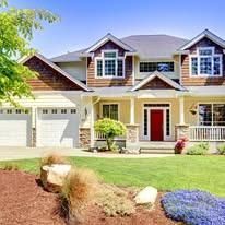 Suburban house with a red front door, white garage, and landscaped yard on a sunny day