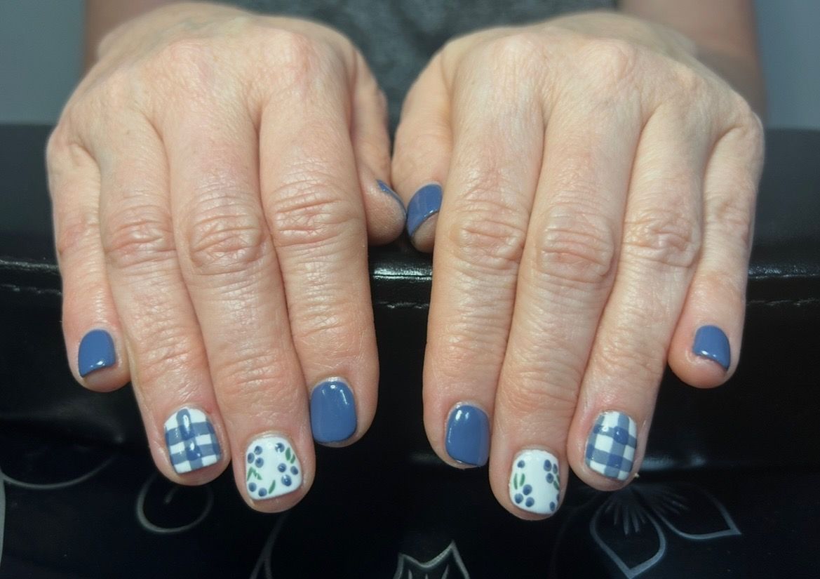 Hands with blue nail polish; two nails have plaid and floral designs.