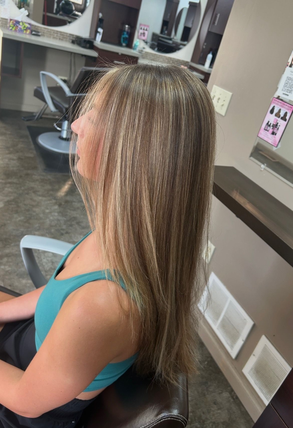 Woman with layered brown hair with blonde highlights in a salon.