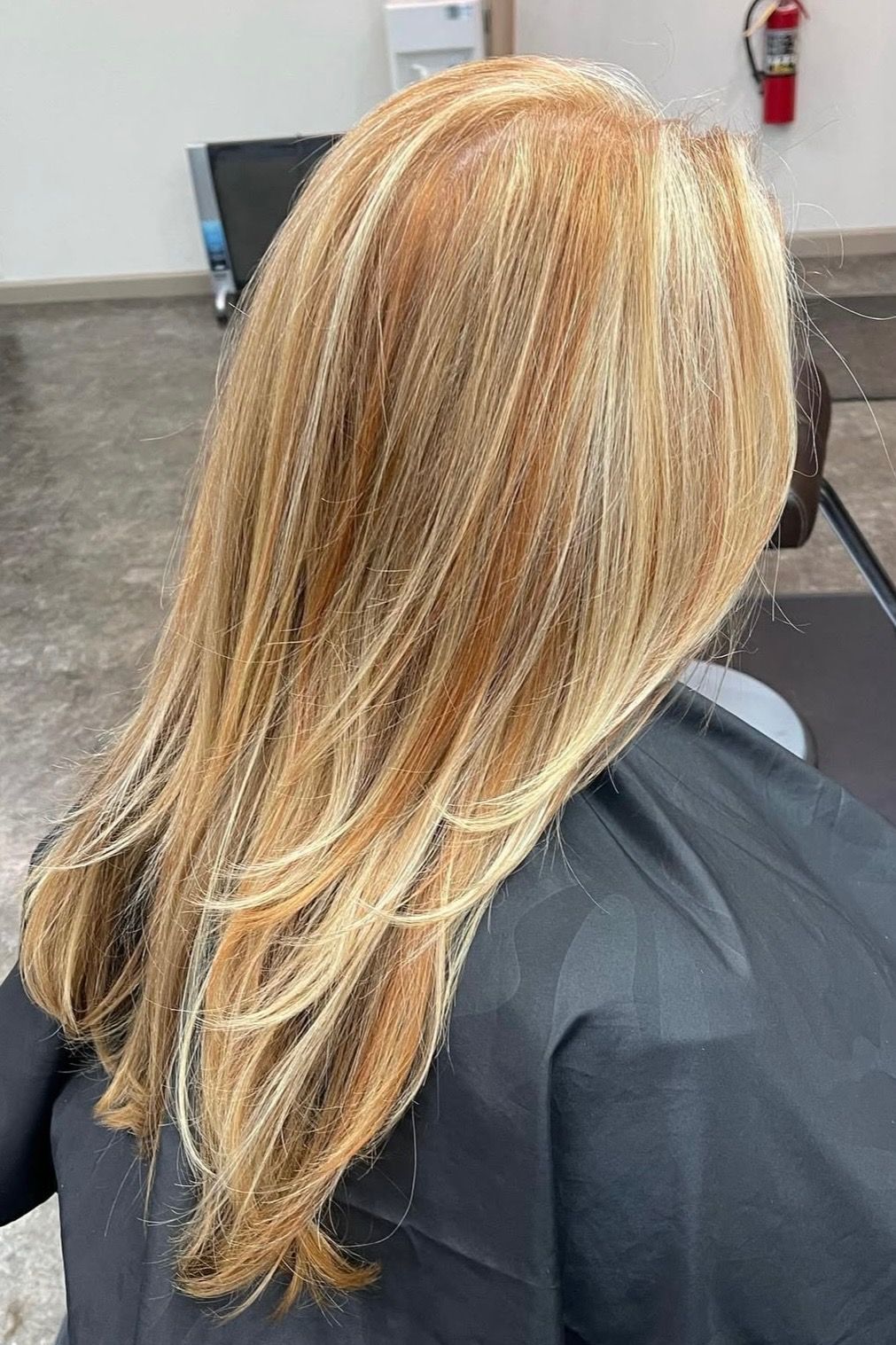 Woman's blonde hair with highlights, sitting in a salon chair.