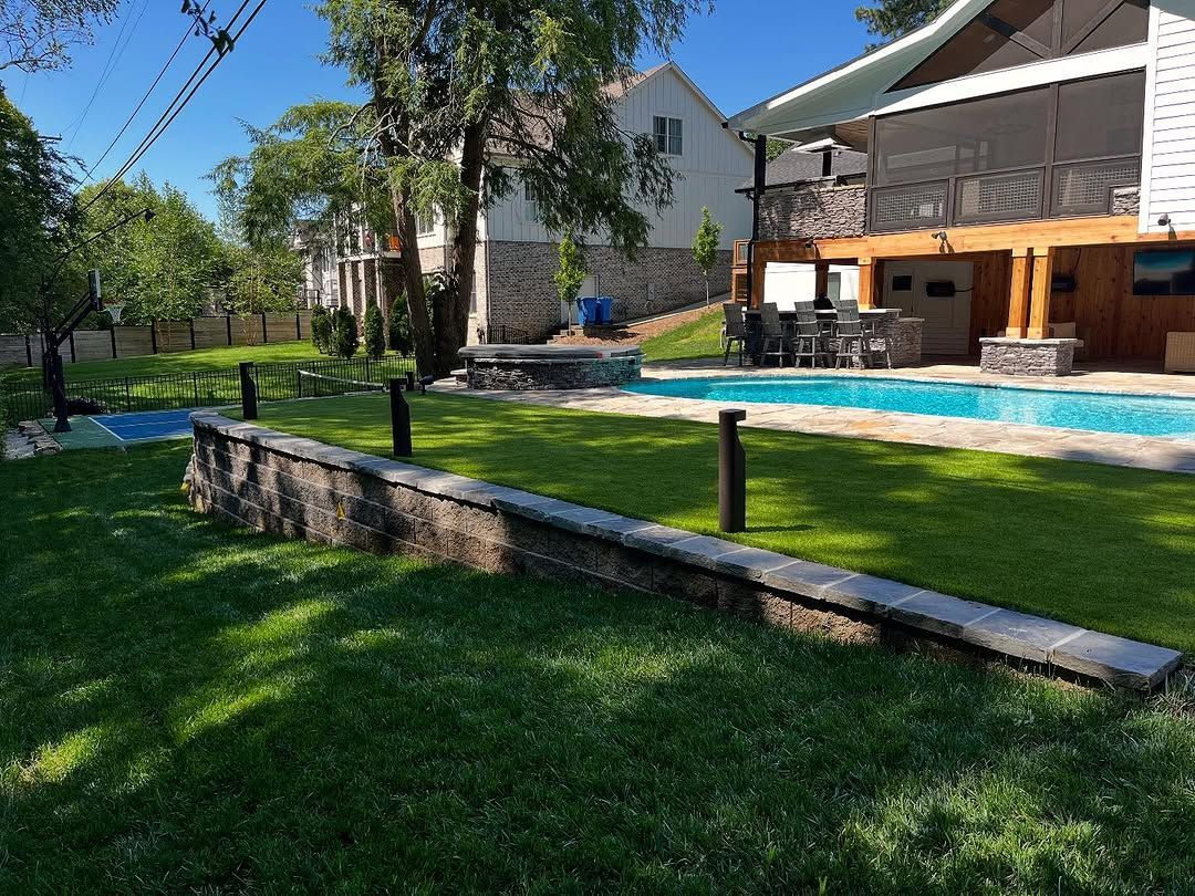 Backyard with a swimming pool, lawn, and a multi-level house on a sunny day.
