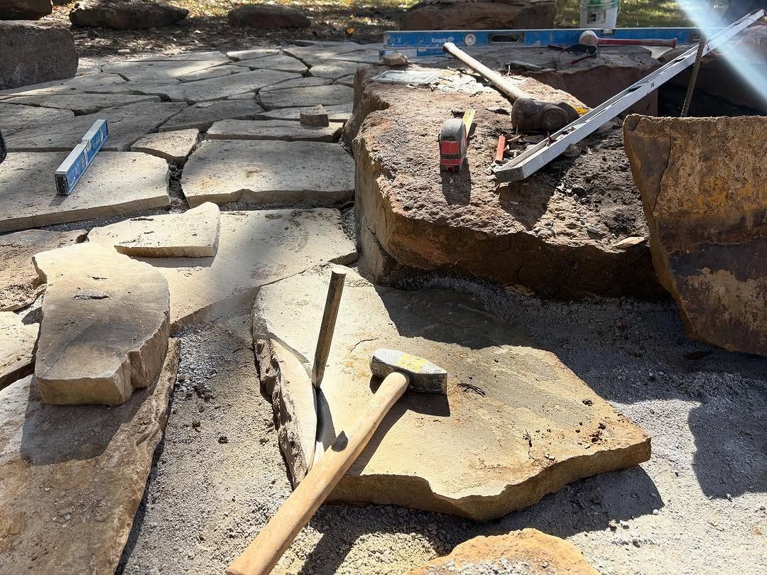 Stone pavers being laid with tools on a sunny day.