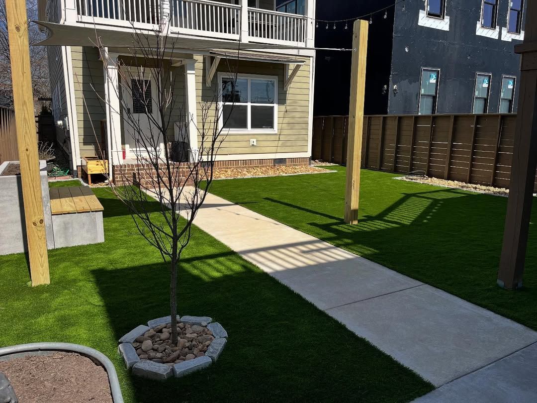 Exterior of a two-story building with a small lawn, a concrete path, and a young tree.