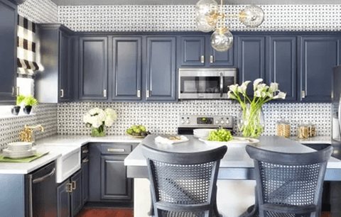 Bright modern kitchen with navy cabinets, white countertops, bar stools, and a vase of flowers
