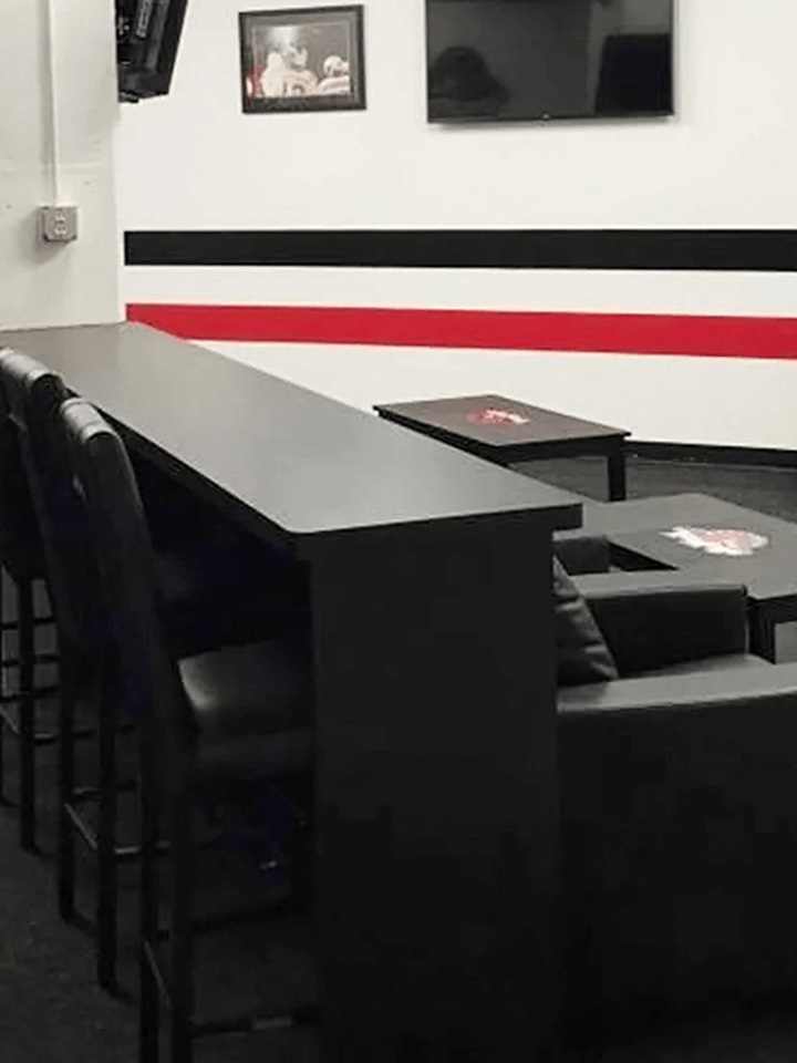 Modern lounge with black seating, low tables, and white walls with red and black stripes.