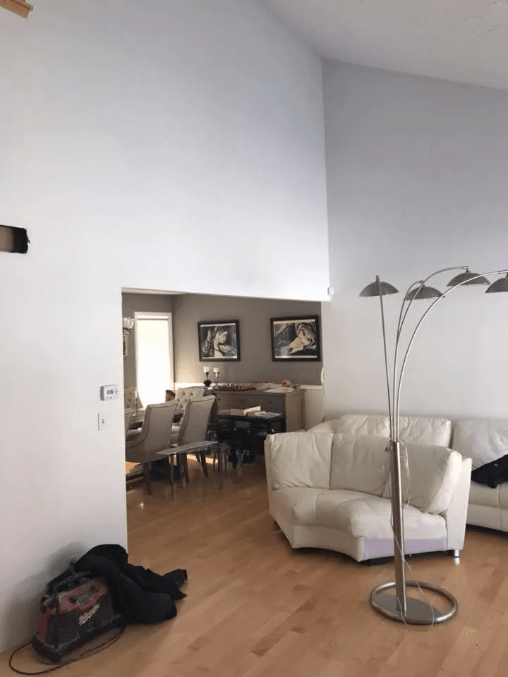 Bright living room with white sofa, floor lamp, and open doorway to a dining area