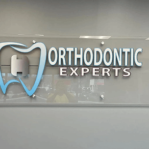 Orthodontic Experts clinic sign with blue tooth logo on a glass wall