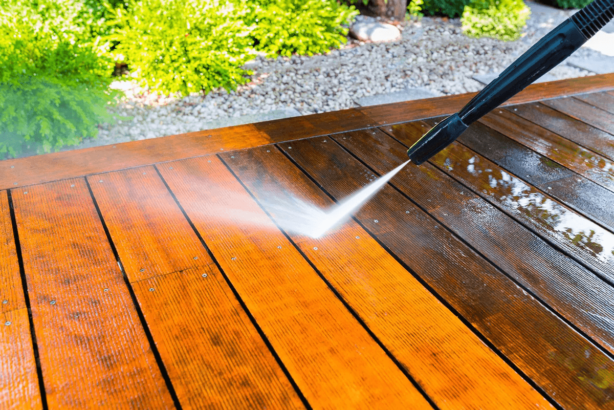 Pressure washing a wet wooden deck with a black hose wand