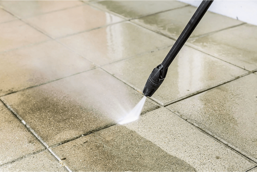 Pressure washing a tiled patio floor with a spray nozzle