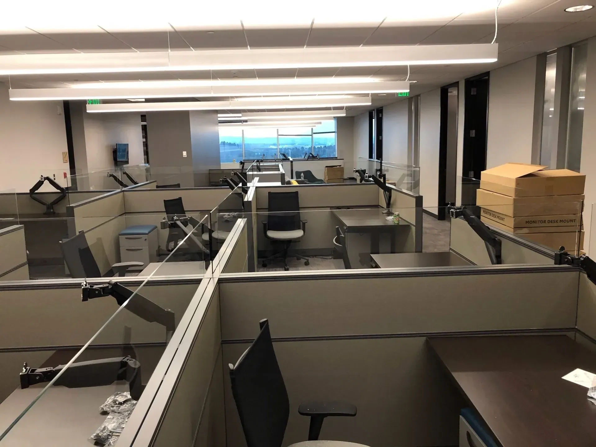 Empty office cubicles with desks, chairs, and stacked moving boxes in a modern workspace