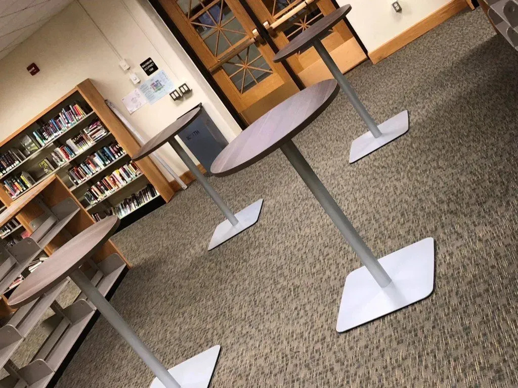 Empty library area with round tables, bookshelves, and carpeted floor in a quiet room