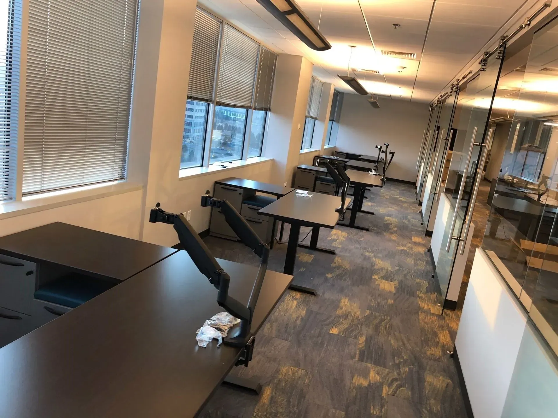 Modern office with desks, swivel chairs, windows, and a conference table in the background