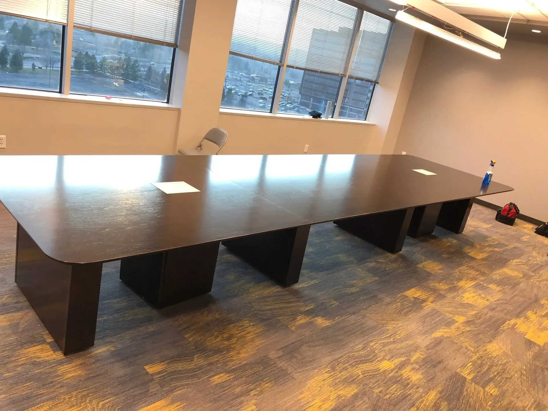 Long conference table in a bright office room with windows and carpeted floor.